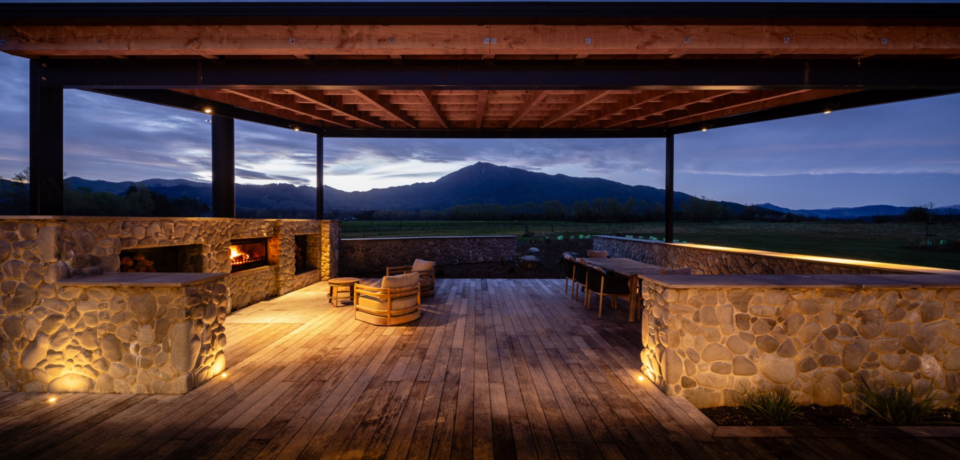 Stone-walled pavilion with fireplace looking out to Mt Peel at dusk
